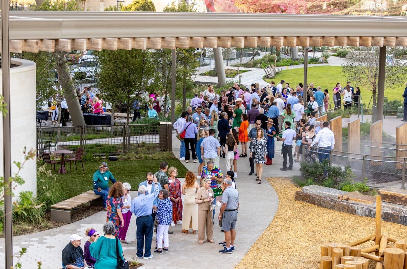 Crowd gathered along a shaded garden path at a park event